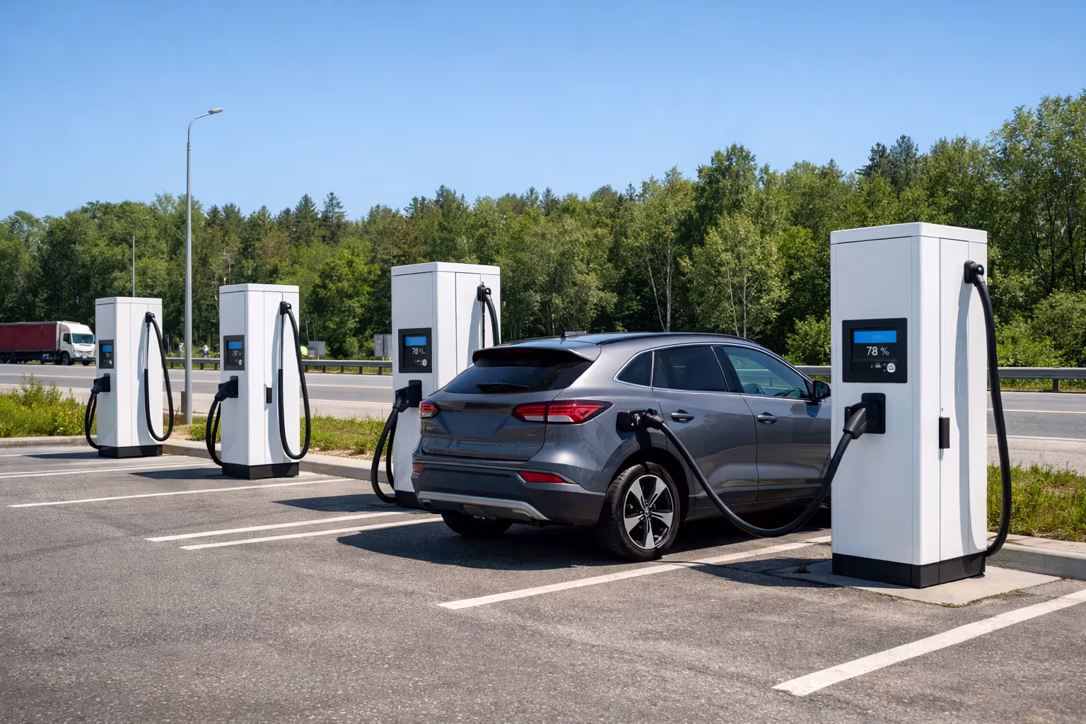 Electric SUV connected to a DC fast charging station at a highway rest stop with multiple charger units visible