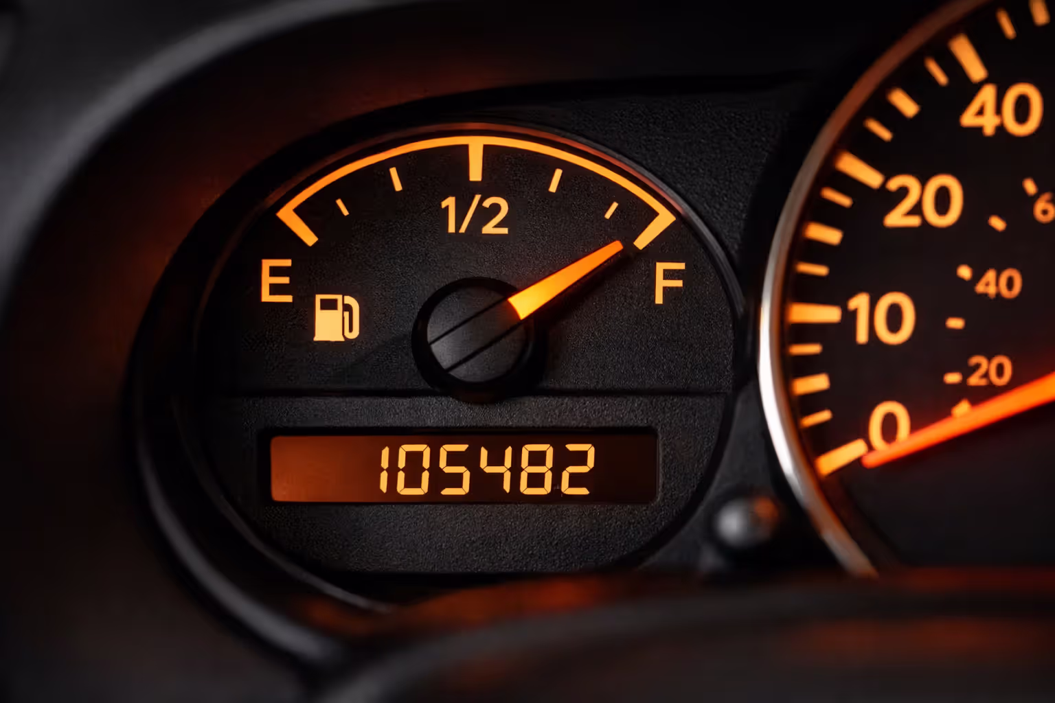 Car dashboard close-up showing fuel gauge and digital odometer mileage display