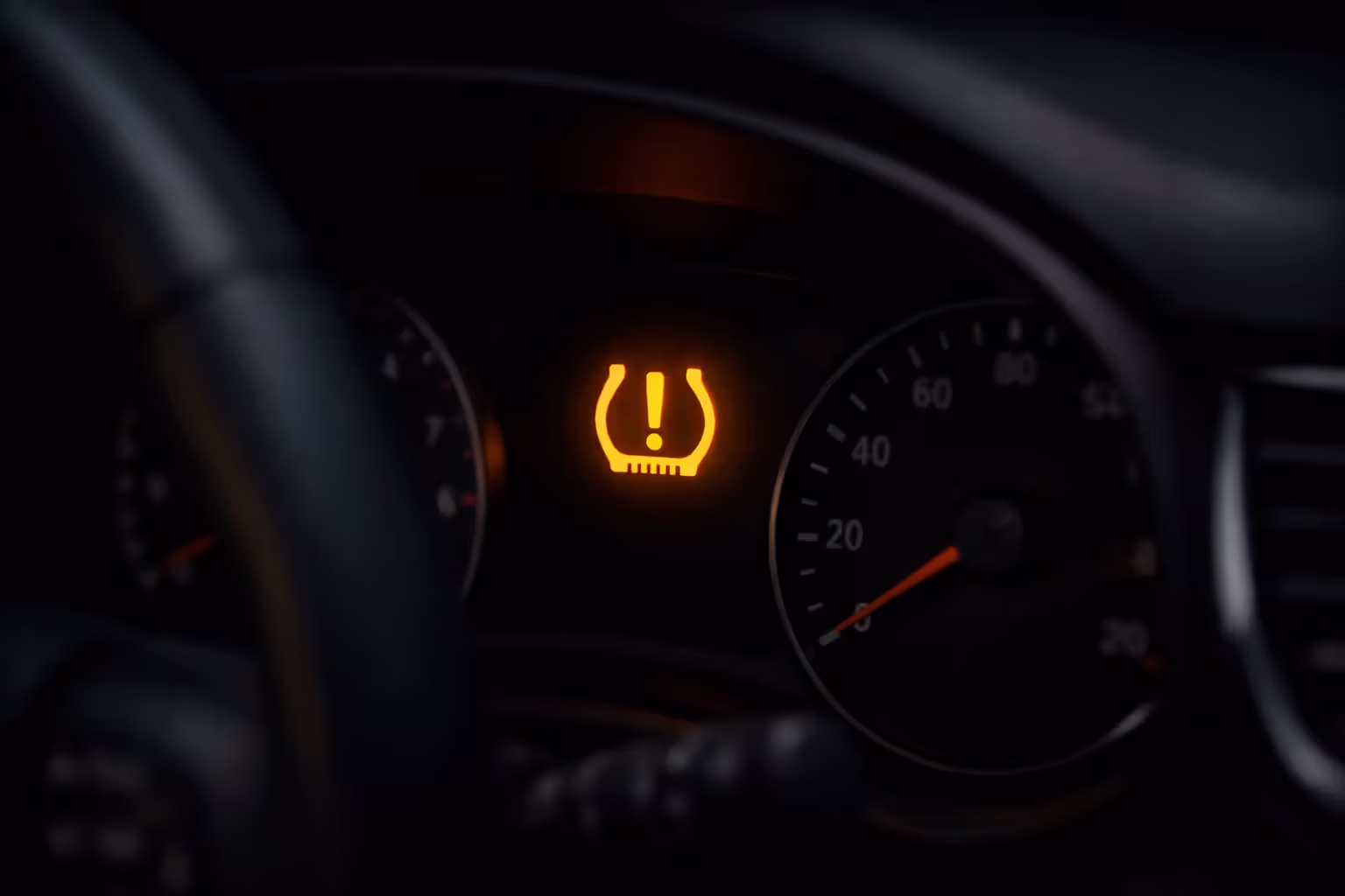 Illuminated TPMS warning light on a car dashboard showing low tire pressure alert symbol
